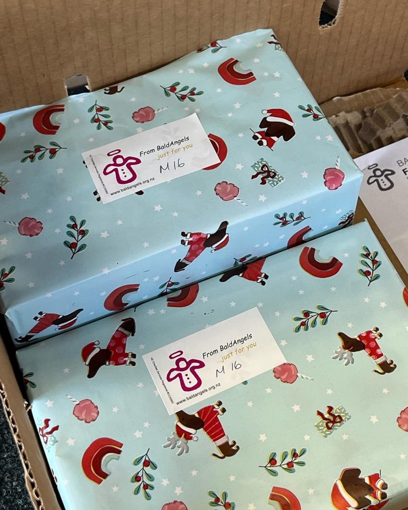 Two xmas wrapped gifts in cartoon patterned blue paper with stickers saying "from Bald Angels"