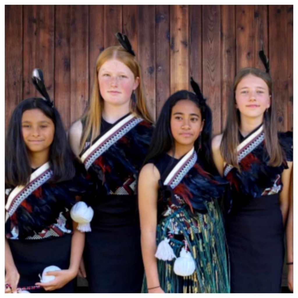 Four girls in Maori costume with poi for kapahaka performance