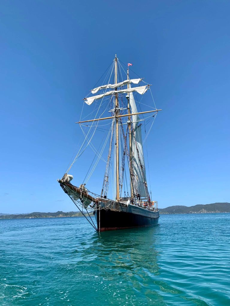 A heritage style sailing ship in turquoise water with a bright blue sky backdrop