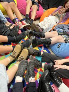 a close up of many legs with boots and shoes on meeting in the centre of the pic.