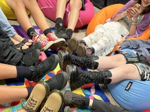 a close up of many legs with boots and shoes on meeting in the centre of the pic.